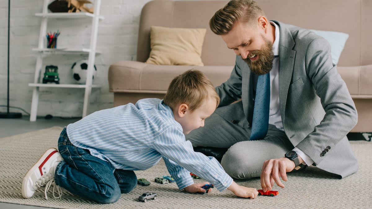 Man dressed in business suit sitting on the floor playing with his son