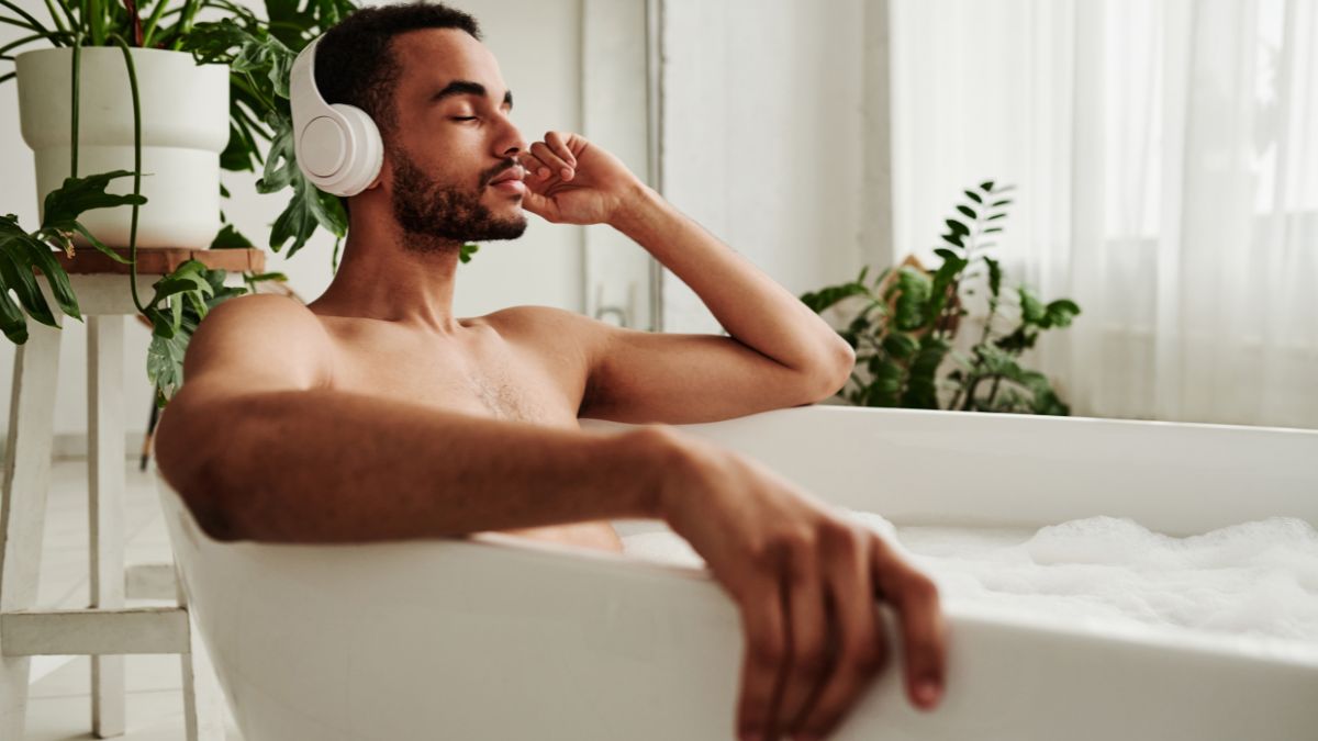 Man sitting in a bubble bath wearing headphones
